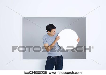 Man looking blank circular sign in hands, smiling View Large Photo Image Stock Photograph - Man looking blank circular sign in hands, smiling. Fotosearch