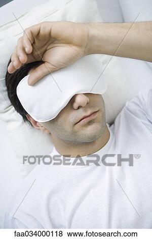 Man lying down with eye mask, hand on head View Large Photo Image Stock Photo - Man lying down with eye mask, hand on head. Fotosearch