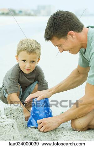 Man making a sand castle with young son View Large Photo Image Stock Photo - Man making a sand castle with young son. Fotosearch