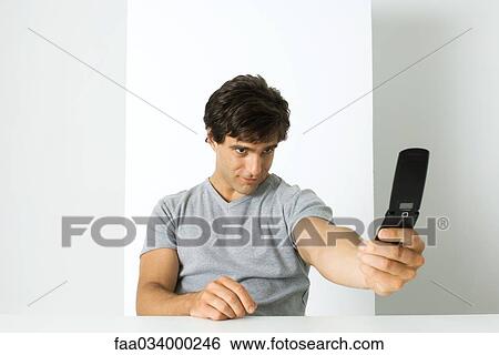 Stock Photograph - Man photographing self with cell phone. Fotosearch