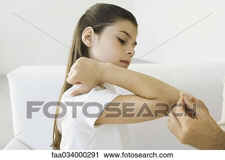Stock Image - Man putting adhesive bandage on girl's elbow, cropped view. Fotosearch