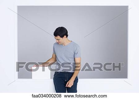 Man sitting on ledge, touching box, smiling View Large Photo Image Stock Photo - Man sitting on ledge, touching box, smiling. Fotosearch