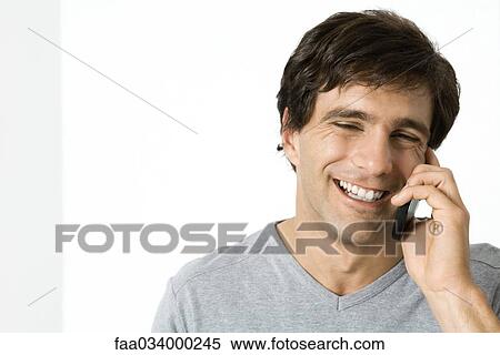 Stock Photography - Man using cell phone, laughing, portrait. Fotosearch