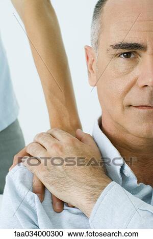 Stock Image - Mature man holding son's hand on shoulder, cropped view. Fotosearch