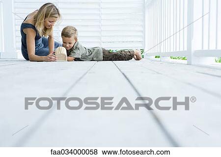 Stock Photo - Mother and son sitting on floor of porch looking at birdhouse. Fotosearch