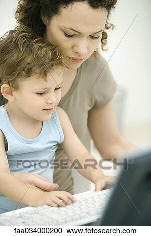 Stock Image - Mother and toddler son typing together on keyboard. Fotosearch