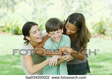 Stock Image - Mother with teenage daughter and son tickling each other. Fotosearch