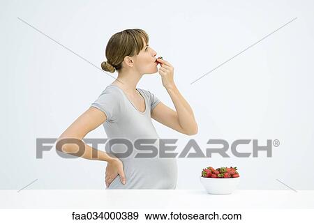 Pregnant woman eating strawberries, side view View Large Photo Image Stock Photo - Pregnant woman eating strawberries, side view. Fotosearch