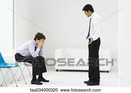 Stock Image - Professional man reprimanding employee, employee covering face with hands. Fotosearch
