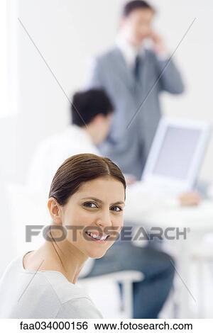 Professional woman in office, smiling over shoulder at camera View Large Photo Image Stock Photograph - Professional woman in office, smiling over shoulder at camera. Fotosearch