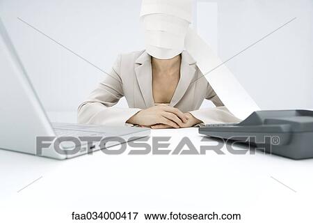 Stock Photo - Professional woman sitting at desk, paper from adding machine wrapped around face. Fotosearch