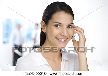 Professional woman using cell phone, smiling at camera View Large Photo Image Picture - Professional woman using cell phone, smiling at camera. Fotosearch