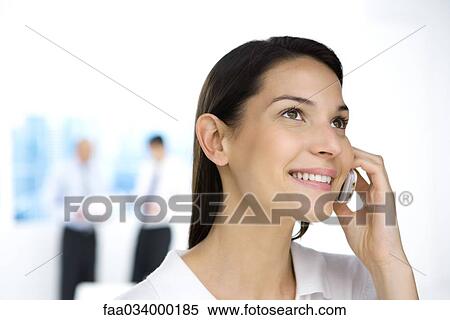 Professional woman using cell phone, looking up, smiling View Large Photo Image Stock Photography - Professional woman using cell phone, looking up, smiling. Fotosearch