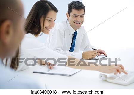 Professionals sitting at table, making conference call View Large Photo Image Stock Image - Professionals sitting at table, making conference call. Fotosearch