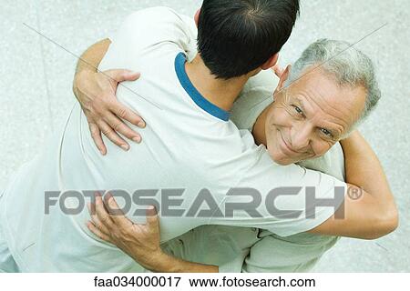 Senior man embracing young man, aerial view View Large Photo Image Stock Photo - Senior man embracing young man, aerial view. Fotosearch