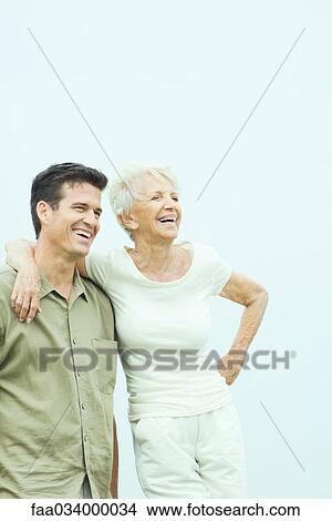 Senior woman with adult son, leaning against him with arm around his shoulder, both looking away smiling View Large Photo Image Picture - Senior woman with adult son, leaning against him with arm around his shoulder, both looking away smiling. Fotosearch