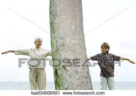 Stock Image - Senior woman with grandson, arms outstretched, exercising outdoors. Fotosearch