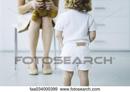 Stock Photo - Shy child facing woman holding stuffed toy, cropped view. Fotosearch