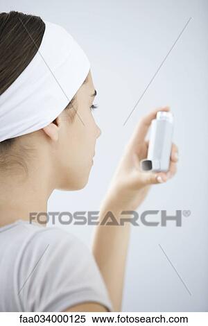 Stock Photography - Teen girl holding asthma inhaler, close-up. Fotosearch