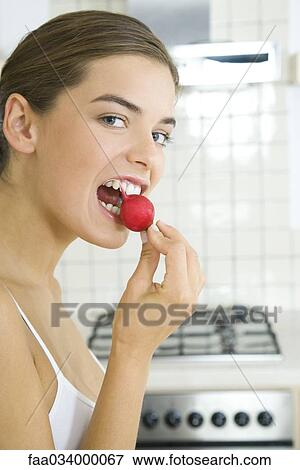 Stock Photo - Woman biting into raw radish. Fotosearch