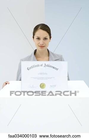 Stock Image - Woman displaying certificate of achievement. Fotosearch