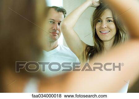 Woman doing her hair with man watching View Large Photo Image Stock Photo - Woman doing her hair with man watching. Fotosearch