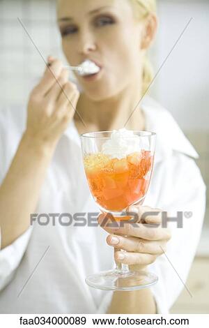 Woman eating jellied fruit dessert with whipped cream View Large Photo Image Stock Photo - Woman eating jellied fruit dessert with whipped cream. Fotosearch