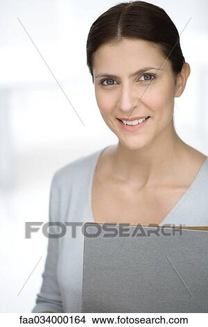 Picture - Woman holding folder, smiling at camera, portrait. Fotosearch