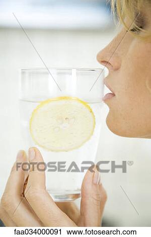 Stock Image - Woman holding glass of water to mouth, eyes closed, profile. Fotosearch