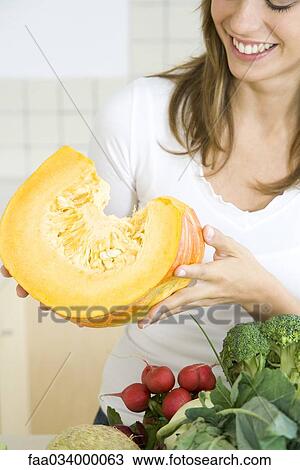 Woman holding large slice of raw pumpkin, smiling View Large Photo Image Stock Image - Woman holding large slice of raw pumpkin, smiling. Fotosearch