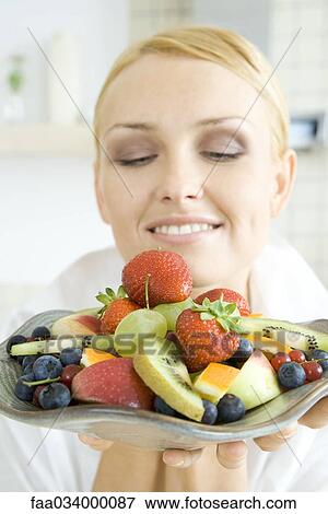 Woman holding plate of fruit salad, smiling, close-up View Large Photo Image Stock Photo - Woman holding plate of fruit salad, smiling, close-up. Fotosearch