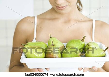 Picture - Woman holding plate of green pears, close-up. Fotosearch