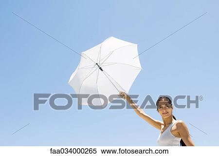 Woman holding up parasol, smiling at camera View Large Photo Image Stock Photography - Woman holding up parasol, smiling at camera. Fotosearch