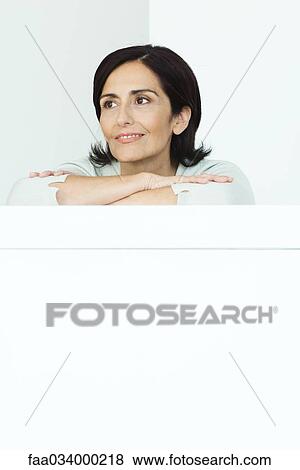 Woman leaning against ledge, arms folded, portrait View Large Photo Image Stock Photo - Woman leaning against ledge, arms folded, portrait. Fotosearch