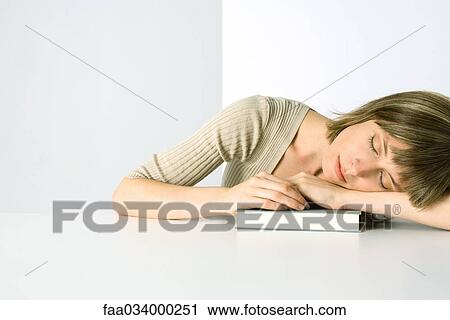 Woman resting arms and head on book, eyes closed View Large Photo Image Stock Image - Woman resting arms and head on book, eyes closed. Fotosearch