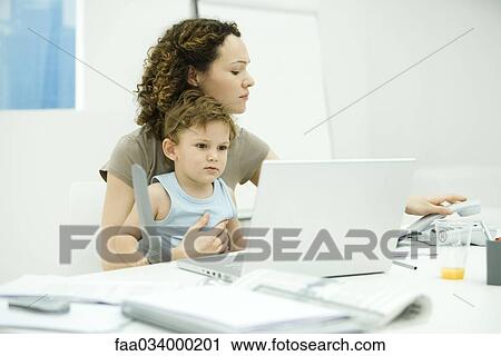 Woman sitting at desk with toddler on her lap, hanging up landline phone View Large Photo Image Stock Image - Woman sitting at desk with toddler on her lap, hanging up landline phone. Fotosearch