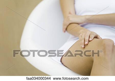 Woman sitting with hand on thigh, cropped view View Large Photo Image Picture - Woman sitting with hand on thigh, cropped view. Fotosearch