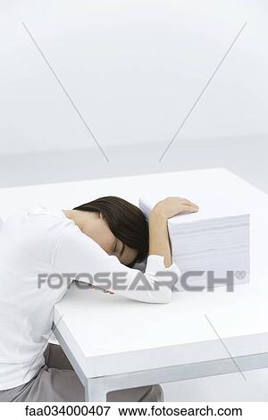 Woman Sleeping At Desk Hand Resting On Large Stack Of Papers