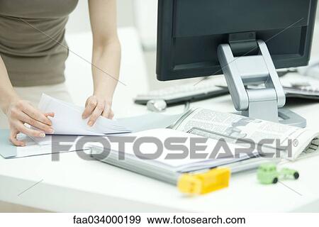 Woman sorting through documents on desk, child's toys in foreground, cropped view View Large Photo Image Stock Photo - Woman sorting through documents on desk, child's toys in foreground, cropped view. Fotosearch