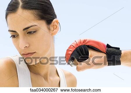 Stock Photo - Woman turning head away from hand in boxing glove, close-up. Fotosearch