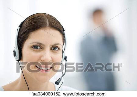 Woman wearing headset, smiling at camera, portrait View Large Photo Image Stock Image - Woman wearing headset, smiling at camera, portrait. Fotosearch