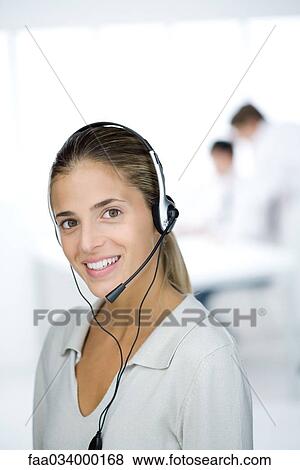 Stock Photo - Woman wearing headset, smiling at camera, portrait. Fotosearch