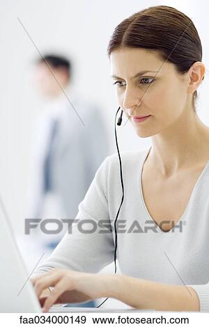 Stock Photo - Woman wearing headset, using laptop computer. Fotosearch