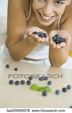 Stock Photo - Woman with hands full of blueberries, smiling. Fotosearch