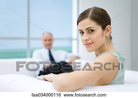 Young businesswoman relaxing on sofa, looking over shoulder at camera View Large Photo Image Stock Photograph - Young businesswoman relaxing on sofa, looking over shoulder at camera. Fotosearch