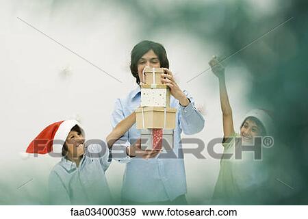 Young man and boys stacking Christmas gifts, smiling, boys wearing Santa hats View Large Photo Image Stock Photo - Young man and boys stacking Christmas gifts, smiling, boys wearing Santa hats. Fotosearch