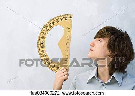 Young man holding up protractor, profile View Large Photo Image Stock Image - Young man holding up protractor, profile. Fotosearch