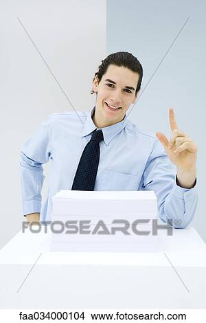 Picture - Young man leaning on counter, gesturing, speaking. Fotosearch