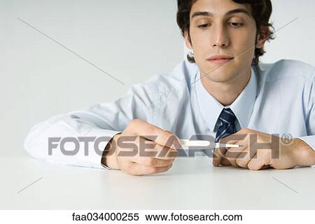 Young man looking at thermometer View Large Photo Image Stock Photography - Young man looking at thermometer. Fotosearch