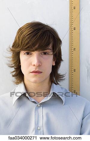 Young man standing in front of ruler, looking at camera View Large Photo Image Stock Image - Young man standing in front of ruler, looking at camera. Fotosearch